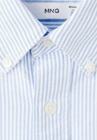 Overhemd met witte en lichtblauwe strepen. Voorzien van een standaardkraag en witte kunststof knopen. Zachte stoftextuur.