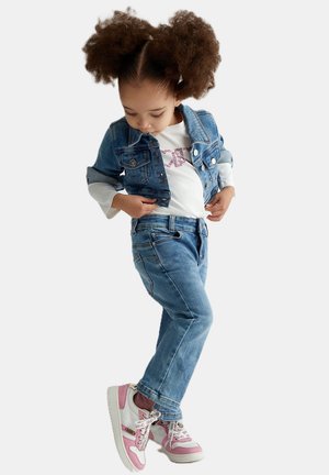 Giubbotto in denim, camicia bianca con scritte rosa, jeans in denim e sneakers rosa. L'outfit presenta tonalità blu classiche e semplici elementi di design.