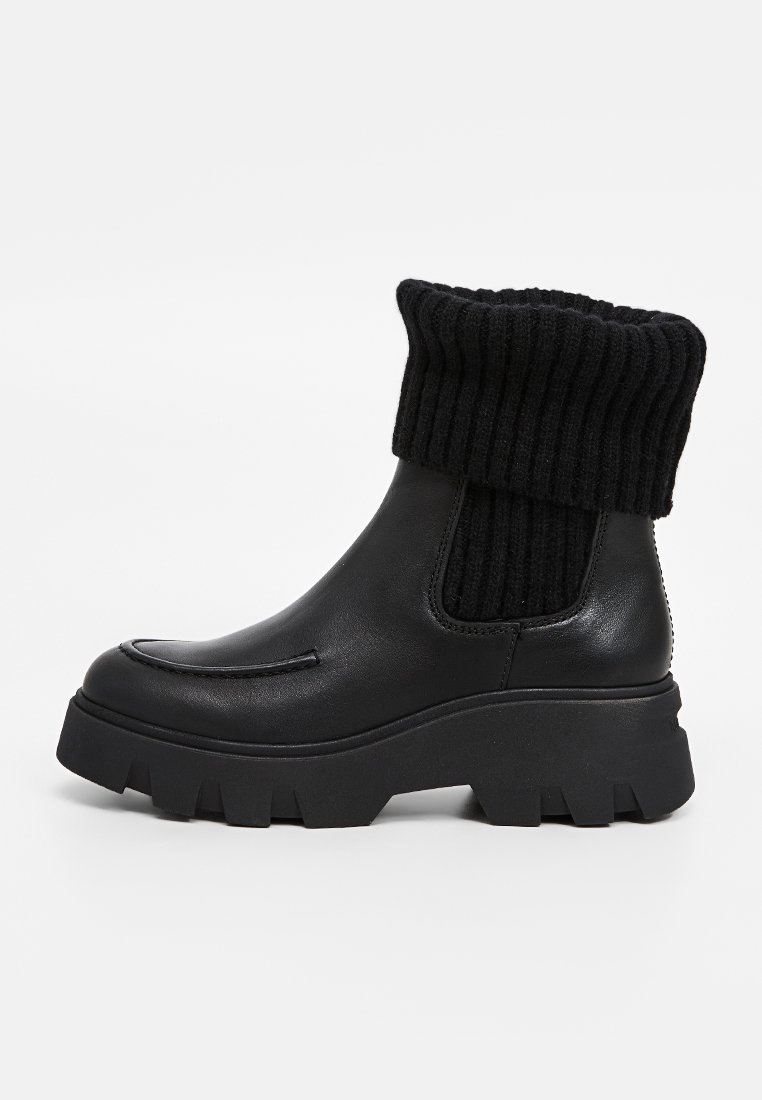 Schwarze Stiefeletten mit einem glatten Lederoberteil und einem gerippten Strickbund. Robuste Sohle mit ausgeprägtem Profil. Minimalistisches Design.