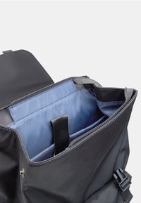 Zaino di tessuto nero con cerniera superiore. L'interno presenta una fodera azzurro chiaro, una tracolla regolabile e un piccolo manico nero.