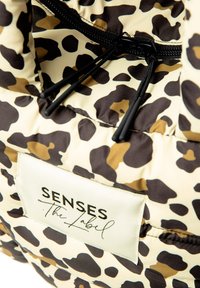 Padded bag with a leopard print pattern in cream, brown, and tan. Features black zippers and a label reading "SENSES The Label."