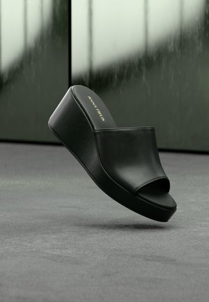 Sandale à plateforme noire en cuir, à bout ouvert, avec le logo Anna Field sur la semelle intérieure, présentée sur un fond sombre flou.