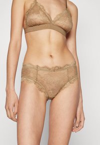 Lacey beige bralette og matchende truser med blomsterfarger, gjennomsiktig materiale og myk, elastisk kant. Delikate blonde detaljer gjennom hele.