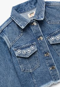 Chaqueta de mezclilla para niños, azul claro con un dobladillo desflecado, adornos de perlas en los bolsillos del pecho y botones de hardware plateado.