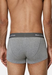 Graue Baumwoll-Boxershorts mit einem schwarzen Bund, der das Logo "Marc O'Polo" zeigt. Glatte Textur, enganliegendes Design und mittellange Beinform.