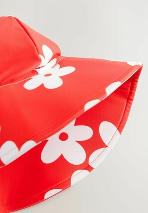 Rote Bucket-Hat aus glattem Stoff mit großen weißen Blumenmustern. Die Krempe ist breit und rund und hat einen kontrastierenden Stich.