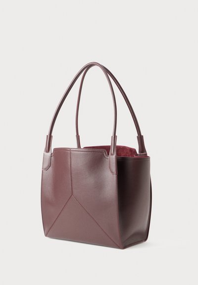 Dark burgundy leather tote bag with dual shoulder straps and subtle panel stitching, standing upright on a white background.