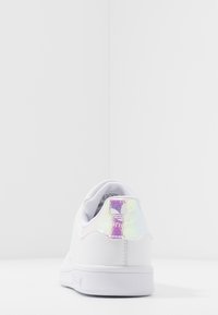 Vita sneaker med en slät yta, med ett holografiskt accent vid hälen och en enkel, klassisk design. Gummisula, minimal detaljer.