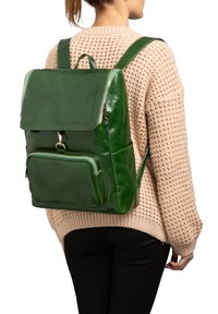 Zaino in pelle verde con design strutturato, chiusura superiore a zip, tasca frontale e texture liscia. Dotato di spallacci regolabili e finitura lucida.