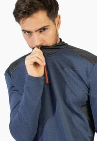 Sudadera de manga larga azul marino con cuello alto, cierre de cremallera, acentos texturizados en los hombros de color negro y tirador de cremallera naranja.