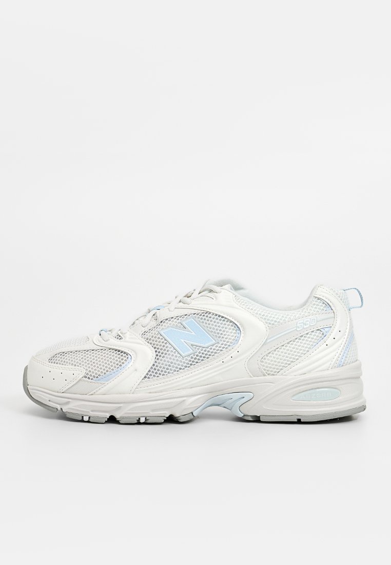 Scarpa sportiva bianca realizzata in rete e materiali sintetici, con un accento blu, punta arrotondata e suola in gomma grigia con dettagli texturizzati.
