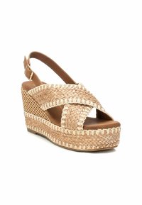 Sandal in rafia marrone con tacco a zeppa, caratterizzato da cinturini incrociati e design a slingback. Presenta un aspetto in juta intrecciata e una soletta liscia.