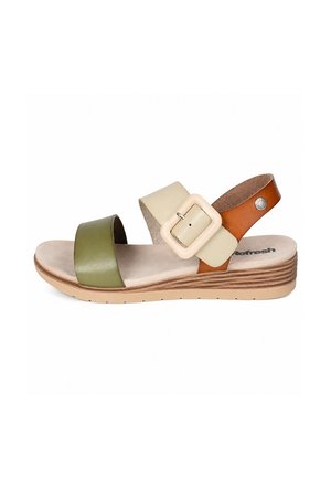 Sandalo open-toe con cinturino frontale verde, cinturino centrale beige con grande fibbia e cinturino marrone alla caviglia su suola bassa in zeppa di legno.