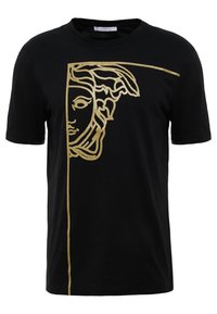 Camiseta negra de algodón con un diseño gráfico dorado de una cara con cabello fluido, dividida por el centro con una línea vertical.