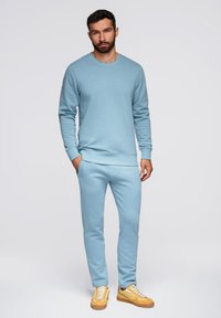 Lichtblauwe sweatshirt en bijpassende joggers gemaakt van zachte stof. De outfit heeft een eenvoudig ontwerp met ribgebreide manchet en zijzakken.