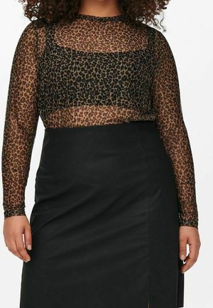 Kvinde iført en langærmet gennemsigtig leopardprint-top over sort bralette kombineret med et sort højtaljet nederdel med slids foran.