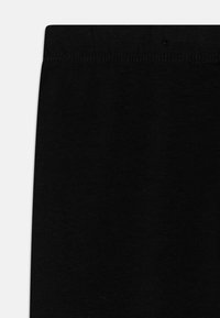 Schwarze Leggings aus einem weichen, glatten Stoff mit einem elastischen Bund. Das Design weist eine schlichte, ungeschmückte Oberflächenstruktur auf.