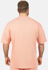 T-shirt rose à manches courtes avec une coupe décontractée, un col arrondi et des coutures standard. Le tissu semble lisse, sans motifs ni accents visibles.