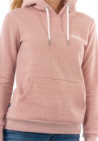 Sudadera con capucha de color rosa claro hecha de tela texturizada, con un bolsillo frontal, cordones blancos y un pequeño logo en el pecho.