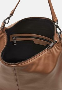 Sac à main en cuir tan avec une finition lisse. L'intérieur présente une doublure noire et une poche zippée, agrémenté de accents en métal argenté.