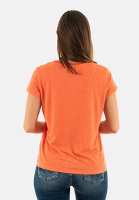 T-shirt en coton orange à manches courtes et col rond, avec une texture lisse et une coupe décontractée. La vue de dos présente un design simple.