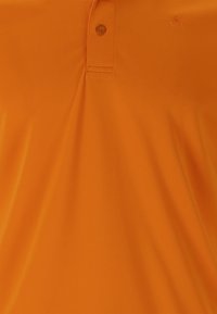 Orange kortärmad polo skjorta i slätt tyg, med en knäppning med två knappar och en liten logotyp nära kragen.