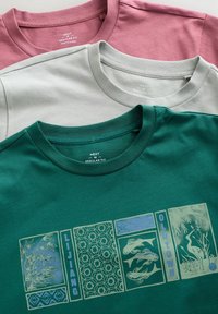 Drei T-Shirts: eines in Pink, eines in Hellgrau und eines in Grün mit einem detaillierten Druck, der ein Design aus Bambus, Fischen und einem Kranich zeigt.