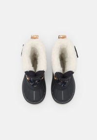 Botas de marina con una suela de goma texturizada, forro blanco esponjoso y acentos decorativos. Presenta una puntera redondeada y un diseño acanalado en la parte superior.