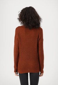 Roodbruine gebreide trui met een losse pasvorm, geribbelde textuur, verlaagde schouders en een ronde zoom, ontworpen voor casual dragen.
