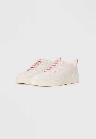 Light beige sneakers with pink accents, rounded toe, flat sole, and lace-up design. Textured material with perforated details.