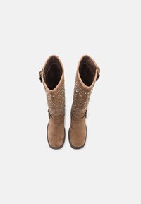 Botas marrones de gamuza hasta la rodilla con joyas transparentes decorativas, una suela resistente y detalle metálico lateral. Textura suave con una apertura ancha en la caña.