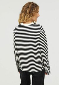 Zwart-wit gestreepte lange mouwen shirt met een ronde hals en een ontspannen pasvorm. Zachte stof met zichtbare stiksels en een licht gebogen zoom.