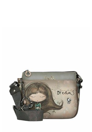 Crossbody-Tasche in gedeckten Farben mit einer grafischen Illustration eines Mädchens, Reißverschlussverschluss, dekorativem Anhänger und verstellbarem Gurt.