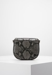 Kulatá kabelka s hadím vzorem v černé a šedé barvě s odnímatelným popruhem. Má texturovaný povrch a zavírání s klopou s jemnými vzorovými detaily.