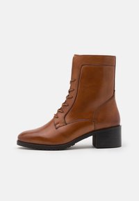 Bottines en cuir marron avec un bout arrondi, un laçage et un solide talon carré. Texture lisse avec des détails de couture sur les côtés.