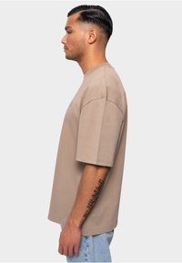 T-shirt en coton beige à manches courtes, col rond et coupe décontractée, présenté de profil sur un fond neutre.