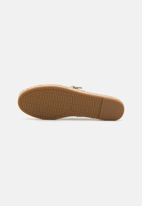Woven tan shoe sole with textured rubber grip, featuring a light beige upper material and a side zipper detail for closure.