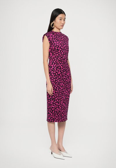 Testhezálló, térdig érő ruha fekete anyagból élénk rózsaszín virágmintával. Rövid ujjú és magas nyakú, fehér cipővel párosítva.