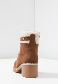 Bottine en suède marron avec un col en fausse fourrure crème, design texturé, détail de fermeture éclair et un talon épais. Vue arrière, mettant en valeur des accents de couture.