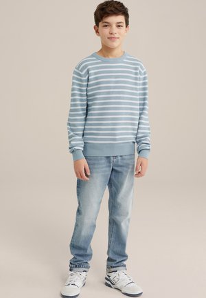 Ljusblå randig tröja med rund hals och ribbade ärmslut, bärs över ljusblå jeans och vita sneakers med blå accenter.