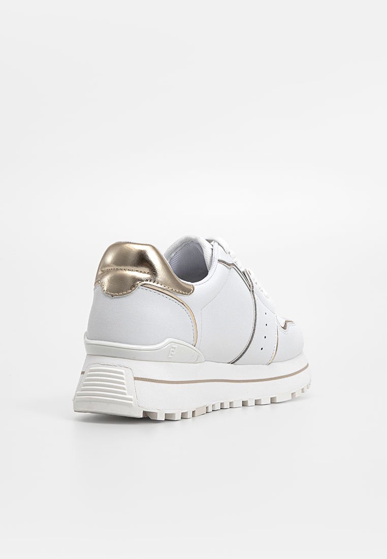 Zapatilla blanca con un acento metálico dorado en el talón, parte superior sintética lisa, suela gruesa y diseño minimalista con costuras sutiles.