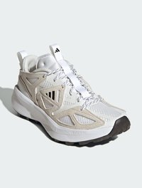 Scarpe da ginnastica bianche che presentano un mix di materiali in rete e suede, una parte superiore testurizzata, punta arrotondata e suola in gomma spessa con un motivo di trazione.