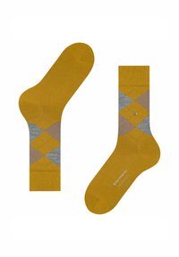 Żółte skarpetki z szaro-beżowym wzorem argyle, z jednolitą piętą i mankietem. Zauważalne logo z diamentowym akcentem z boku.