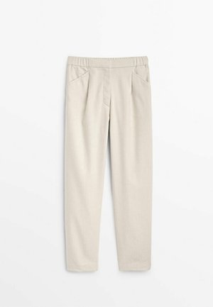 Beige broek van een zacht materiaal, met een elastische tailleband, twee voorzakken en een tapered leg ontwerp.