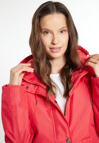 Red waterproof jacket with a hood, elastic cuffs, zipper closure, and adjustable drawstrings. Smooth texture, lightweight fabric, versatile design.