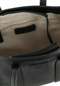 Sac en cuir noir avec une surface texturée, doublure beige, poches zippées et doubles poignées, conçu pour allier fonctionnalité et style.