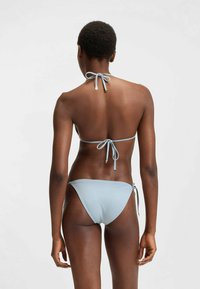 Ljusblå bikini med knytningar i nacken och bak. Överdelens design är halterneck, medan underdelen har justerbara sidoknytningar och en slank passform.