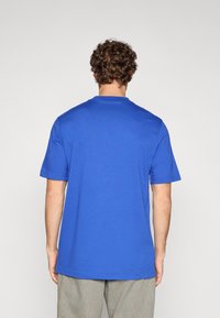 Tricou albastru din bumbac, cu mâneci scurte și decolteu rotund, având o textură netedă și croială lejeră, văzut din spate.