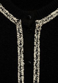 Czarny kardigan o teksturowanym wykończeniu, z wyraźną białą i czarną ozdobną lamówką z przodu oraz trzema czarnymi guzikami.