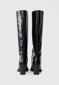 Μαύρες μπότες μέχρι το γόνατο από λουστρίνι με υφή κροκόδειλου, με τακούνι block και εφαρμοστή σχεδίαση.